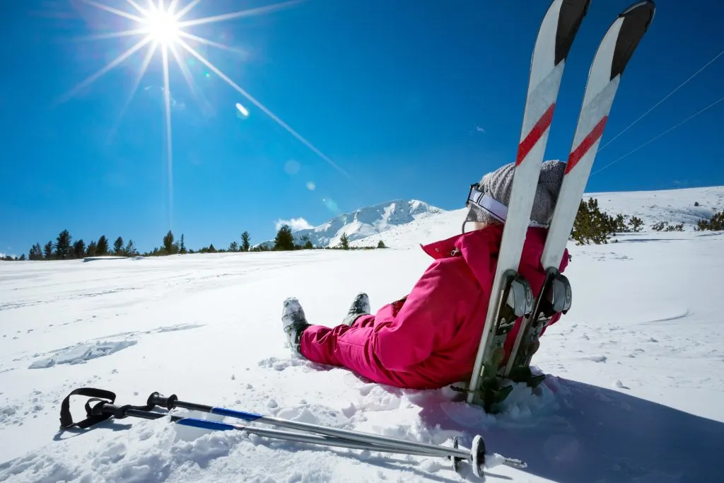 Skiløper som slapper av på en solrik dag i vintersesongen